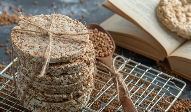 Stack of crispbread, buckwheat and book on marble surface