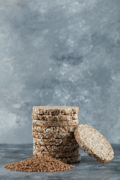 Free photo stack of crispbread and pile of buckwheat on marble surface