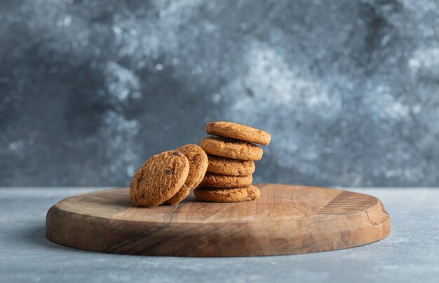 Stack of delicious chocolate chip cookies on wooden board