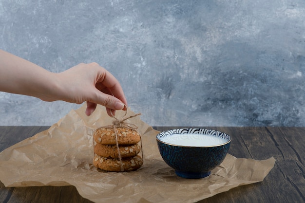 Stack of delicious cookies with cereals and a bowl of fresh milk.