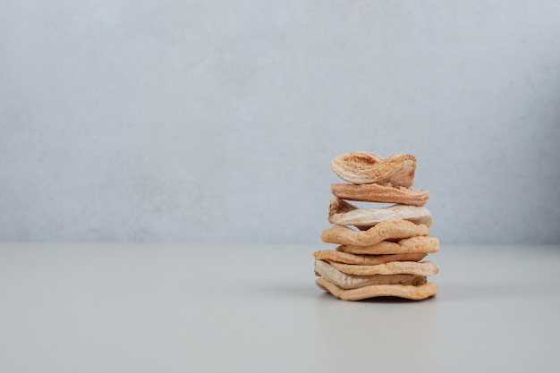 Stack of dried apple chips on white surface