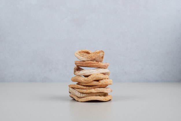 Stack of dried apple chips on white surface