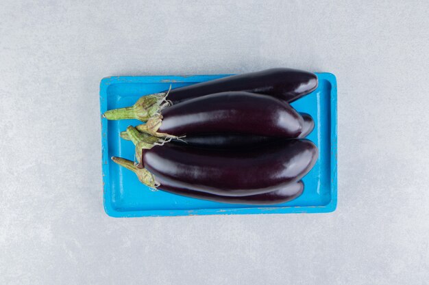 A stack of eggplants on a tray on the marble surface