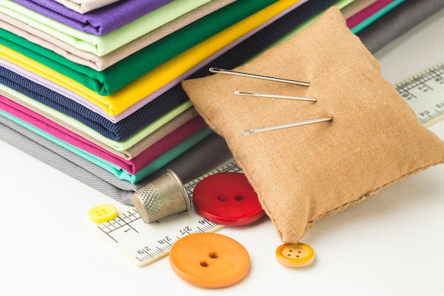 Free photo stack of fabric with needles and buttons