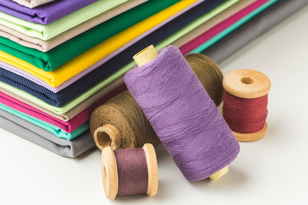 Free photo stack of fabric with spools of thread