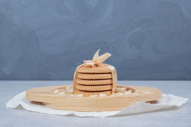 Stack of festive biscuits and peanuts on wooden plate. 