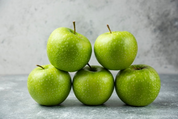 Stack of fresh apples on marble.