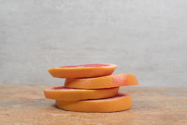 Stack of grapefruit slices on marble table.