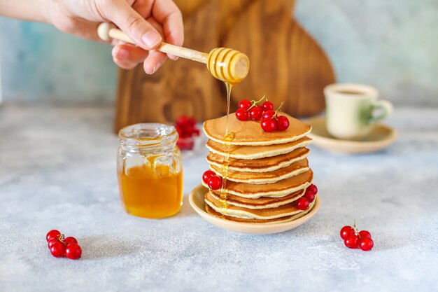 Stack of homemade pancakes with honey syrup and berries