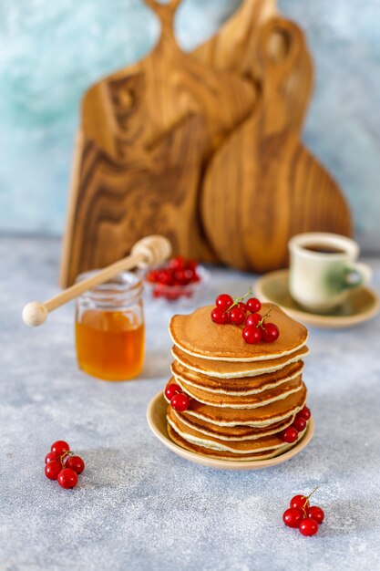 Stack of homemade pancakes with honey syrup and berries