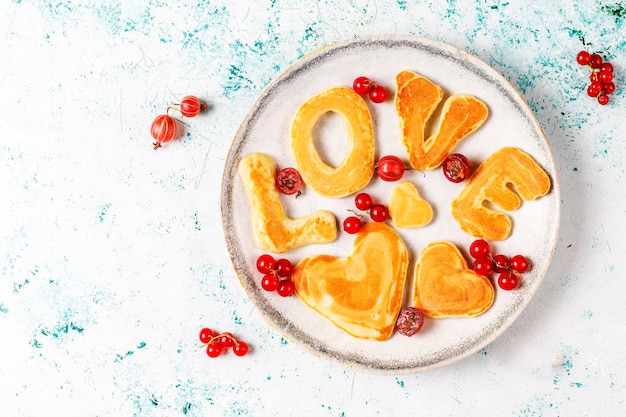 Free photo stack of homemade pancakes with honey syrup and berries.