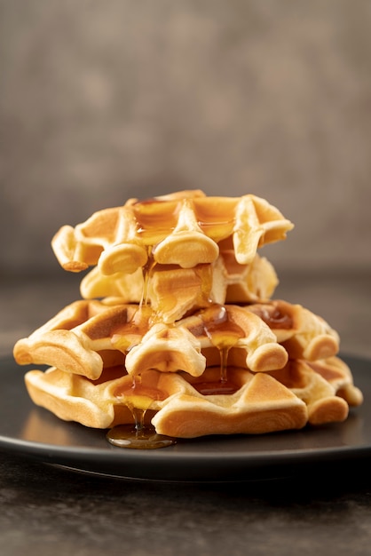 Stack of honey covered waffles on plate with copy space