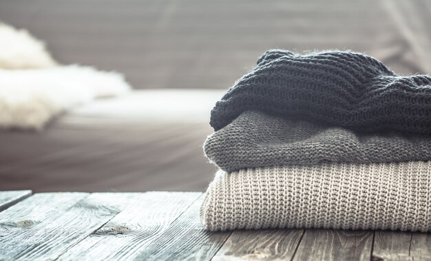 A stack of knitted sweaters on a wooden table