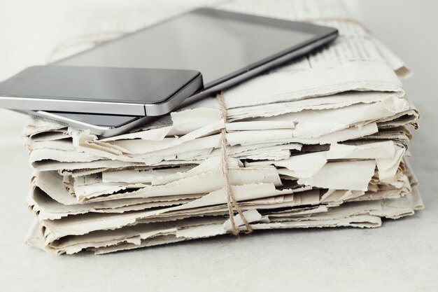 Stack of newspapers with digital tablet and smartphone