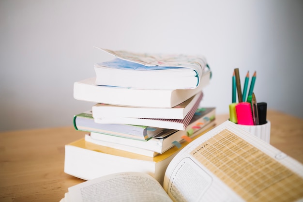 Free photo stack of notebooks and cup with pencils