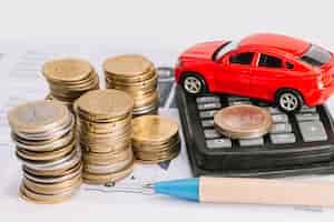 Бесплатное фото Стек монет; калькулятор; игрушечный автомобиль и ручка на шаблоне