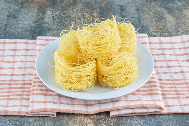 Una pila di pasta sul piatto sull'asciugamano, sulla superficie di marmo.