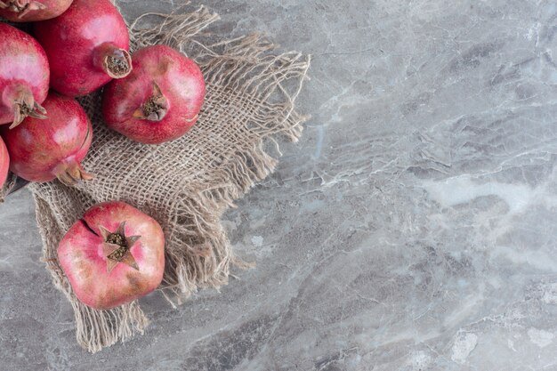 Stack of pomegranates on a piece of cloth on marble.