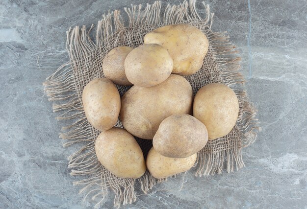 A stack of potatoes on the trivet on the marble table. 