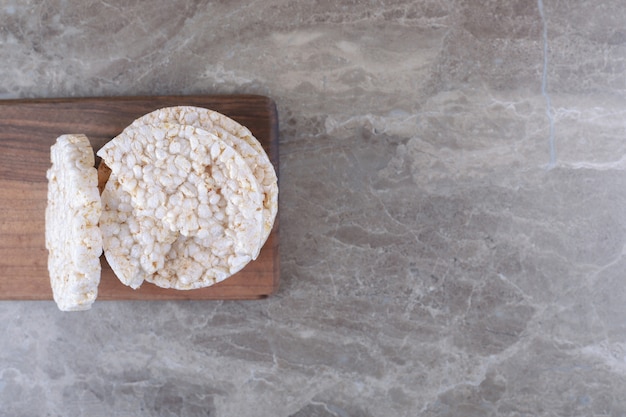 A stack of puffed rice cakes on the wooden tray, on the marble surface