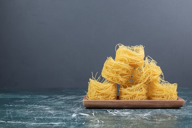 Stack of raw spaghetti nests on wooden board. High quality photo