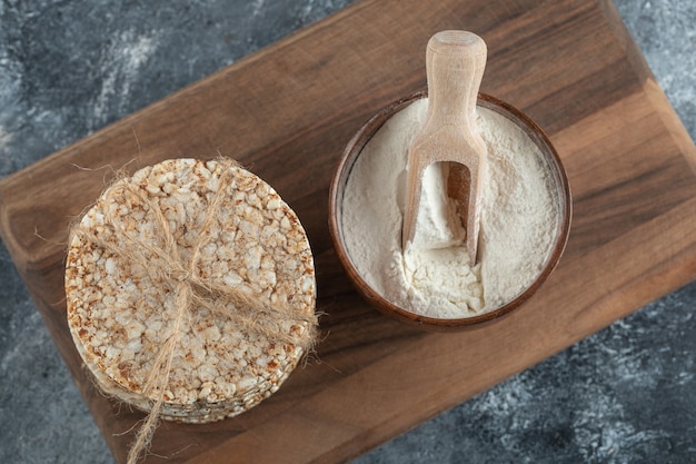 Stack of rice cakes and bowl of flour on wooden board