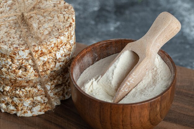 Stack of rice cakes and bowl of flour on wooden board