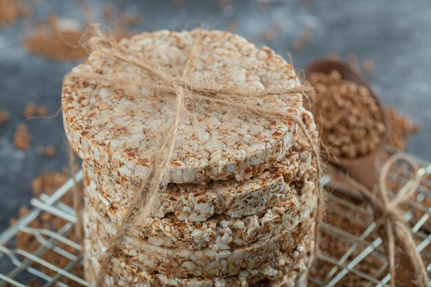 Stack of rice cakes and scattered buckwheat on marble surface