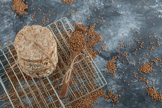 Stack of rice cakes and scattered buckwheat on marble surface