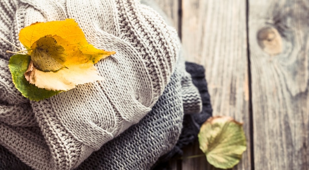 A stack of sweaters and autumn leaves