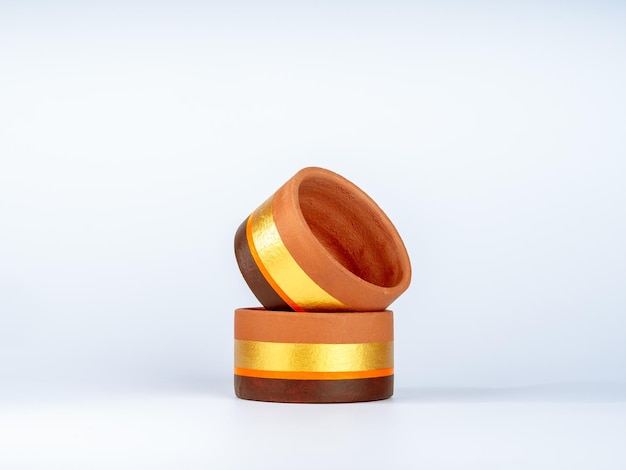 Stack of two empty terra cotta pots isolated on white background. the twin modern terracotta plant pots, the round shape is painted with gold, orange, and brown color bars.