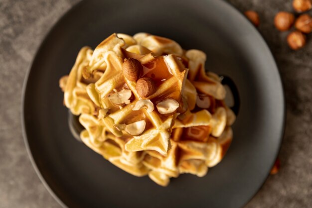 Stack of waffles on plate with honey and hazelnuts