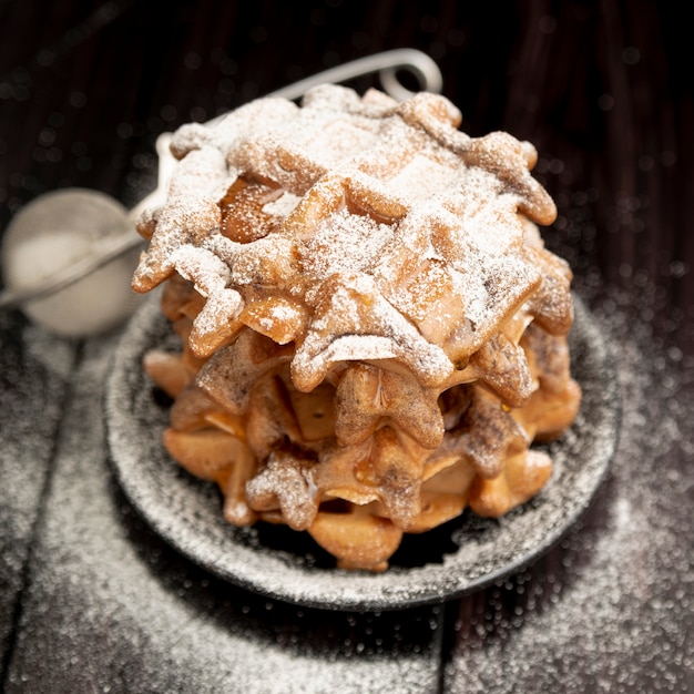 Stack of waffles on plate with powdered sugar