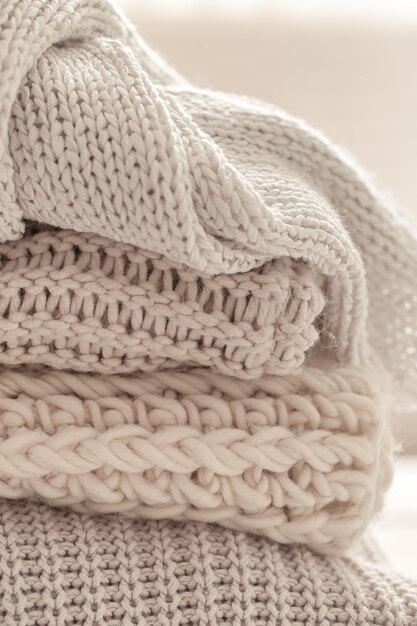 A stack of warm knitted items on blurred white background.
