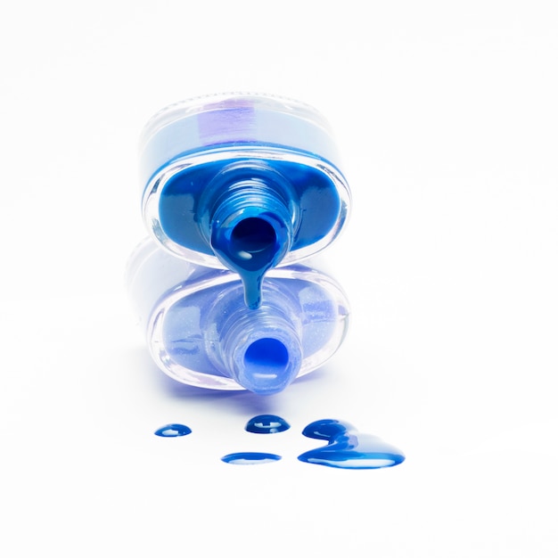 Stacked blue nail polish dripping on white backdrop