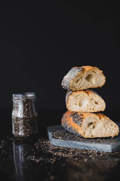 Stacked of bread slices with chia seeds on rock against black background