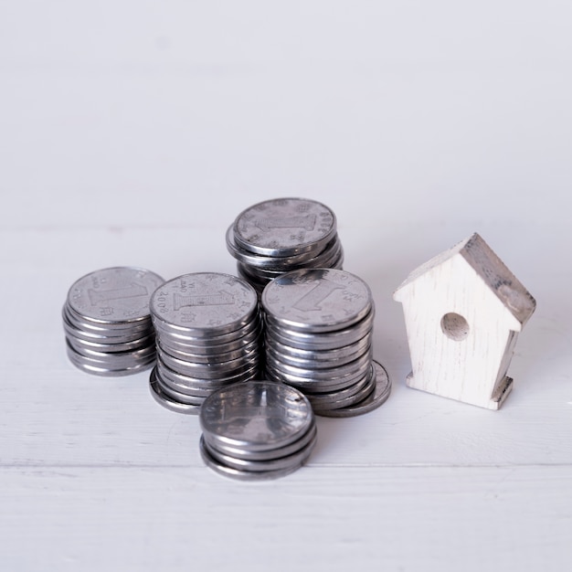 Free photo stacked of chinese coin one yuan with miniature wooden birdhouse on wooden backdrop