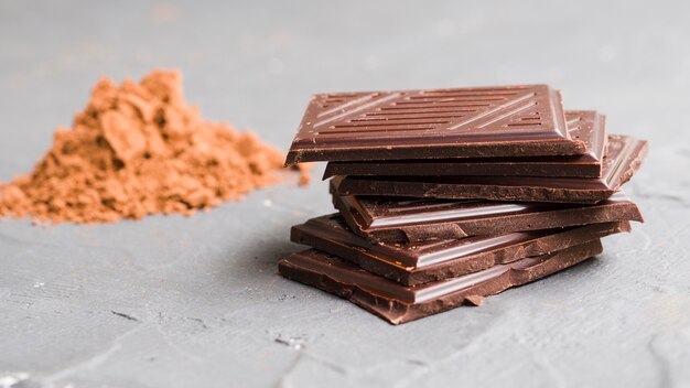 Stacked chocolate pieces next to cocoa powder