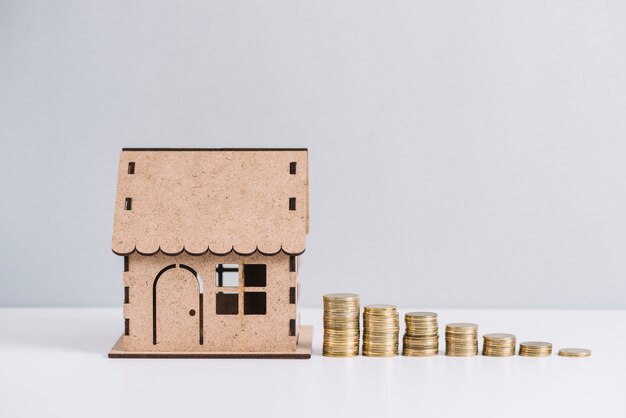 stacked coins near house model against white background
