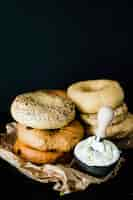 Free photo stacked of different type of bagel with cheese in the bowl against black backdrop