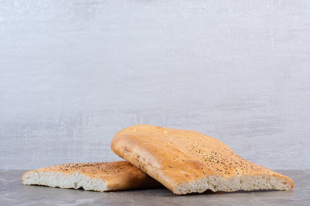 Stacked loaves of crisp half-sliced tandoori bread on marble.