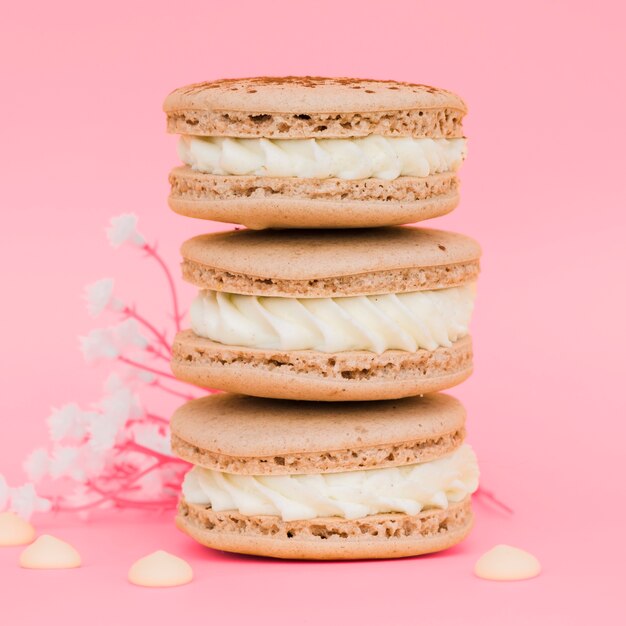 Stacked of macaroons with flowers against pink background