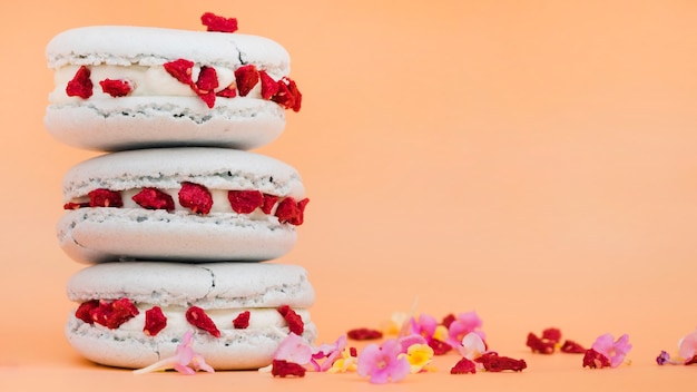 Stacked of macaroons with flowers on beige background