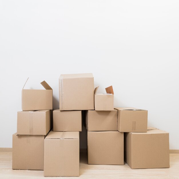 Stacked of moving cardboard boxes against white wall