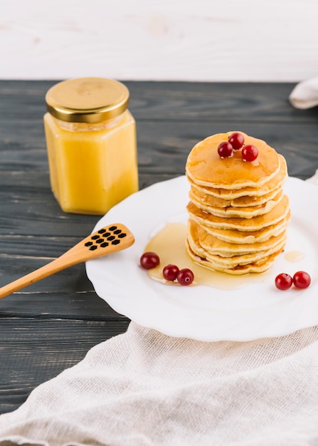 Stacked of pancake with honey and red currant berries on plate