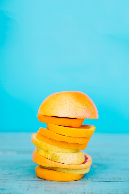 Stacked slices of orange and lemon fruit on blue wooden surface