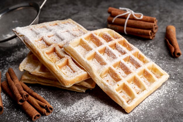 Stacked waffles with powdered sugar and cinnamon sticks