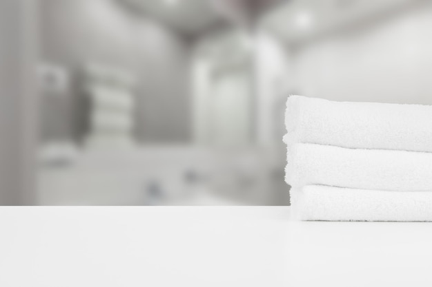 Stacked white spa towels on table against blurred background
