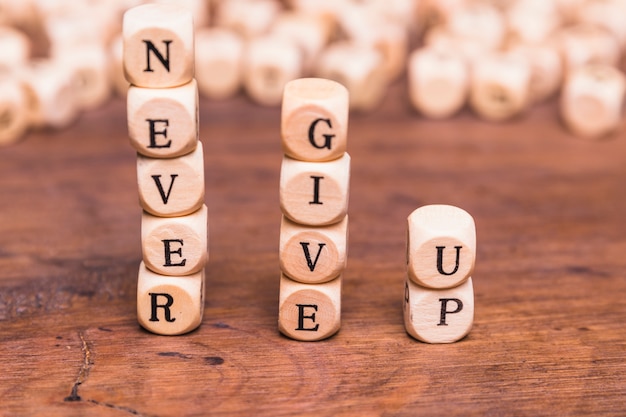 Stacked of wooden blocks with word never give up on wooden desk