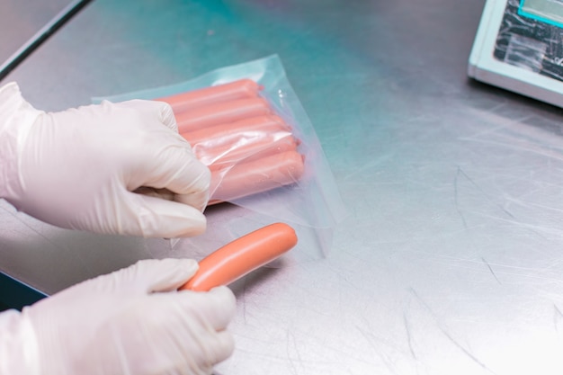 Staff member packing sausages into plastic pockets.